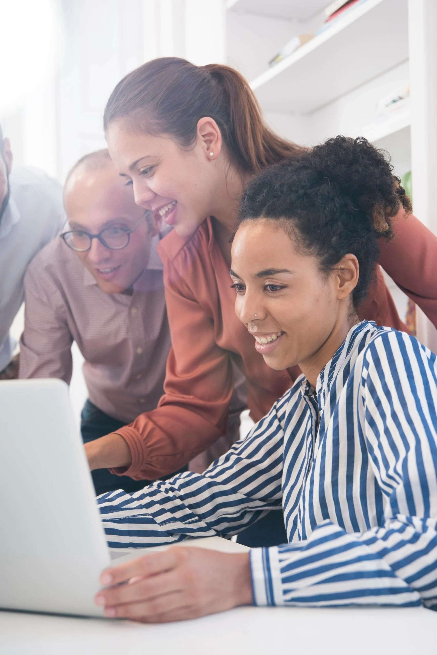 Businesswomen And Men Looking At Laptop At Boardroom Table